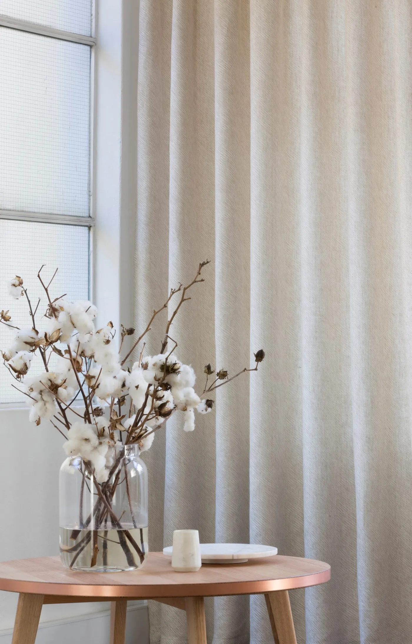 Mokum Grassland textured curtain fabric behind cotton branches